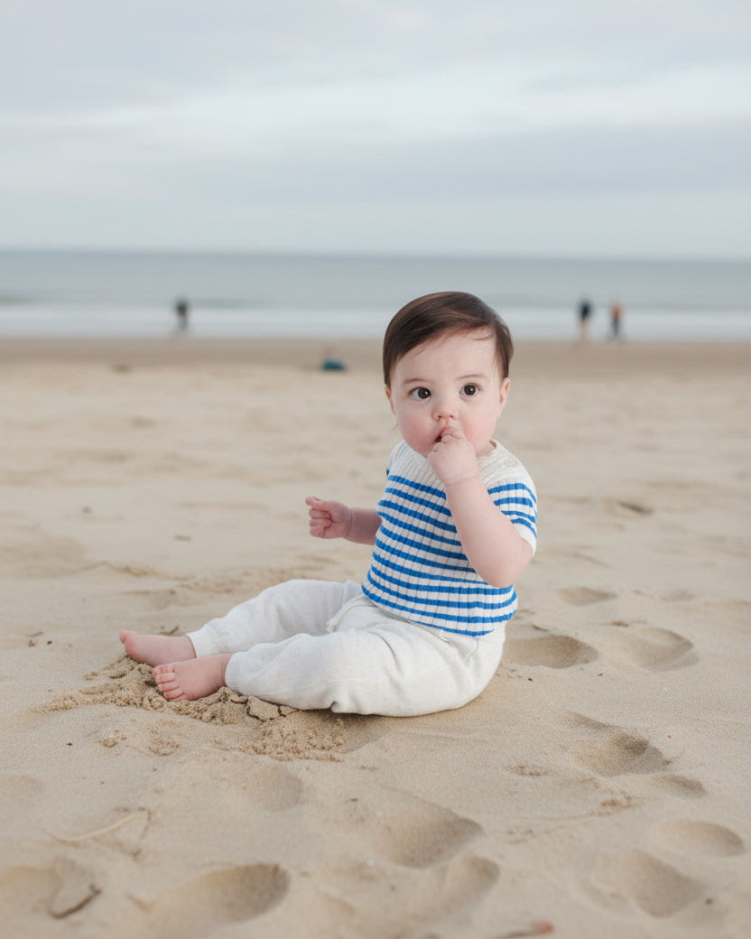 Bébé portant une marinière et assis sur la plage